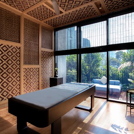 The Ruma Hotel And Residences Kuala Lumpur Kültér fotó The photo displays a tranquil room designed for relaxation or therapy. The room features a massage table centered in the space, with elegant wooden accents. The walls are adorned with intricate geometric patterns, contributing to a serene atmosphere.