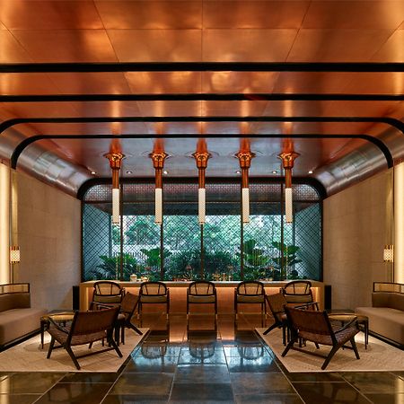 The Ruma Hotel And Residences Kuala Lumpur Kültér fotó The image shows a stylish interior space with a modern and elegant design. The walls have a sleek, warm-toned finish, and there are large windows that provide natural light. The ceiling features striking architectural lines, likely in a metallic mate