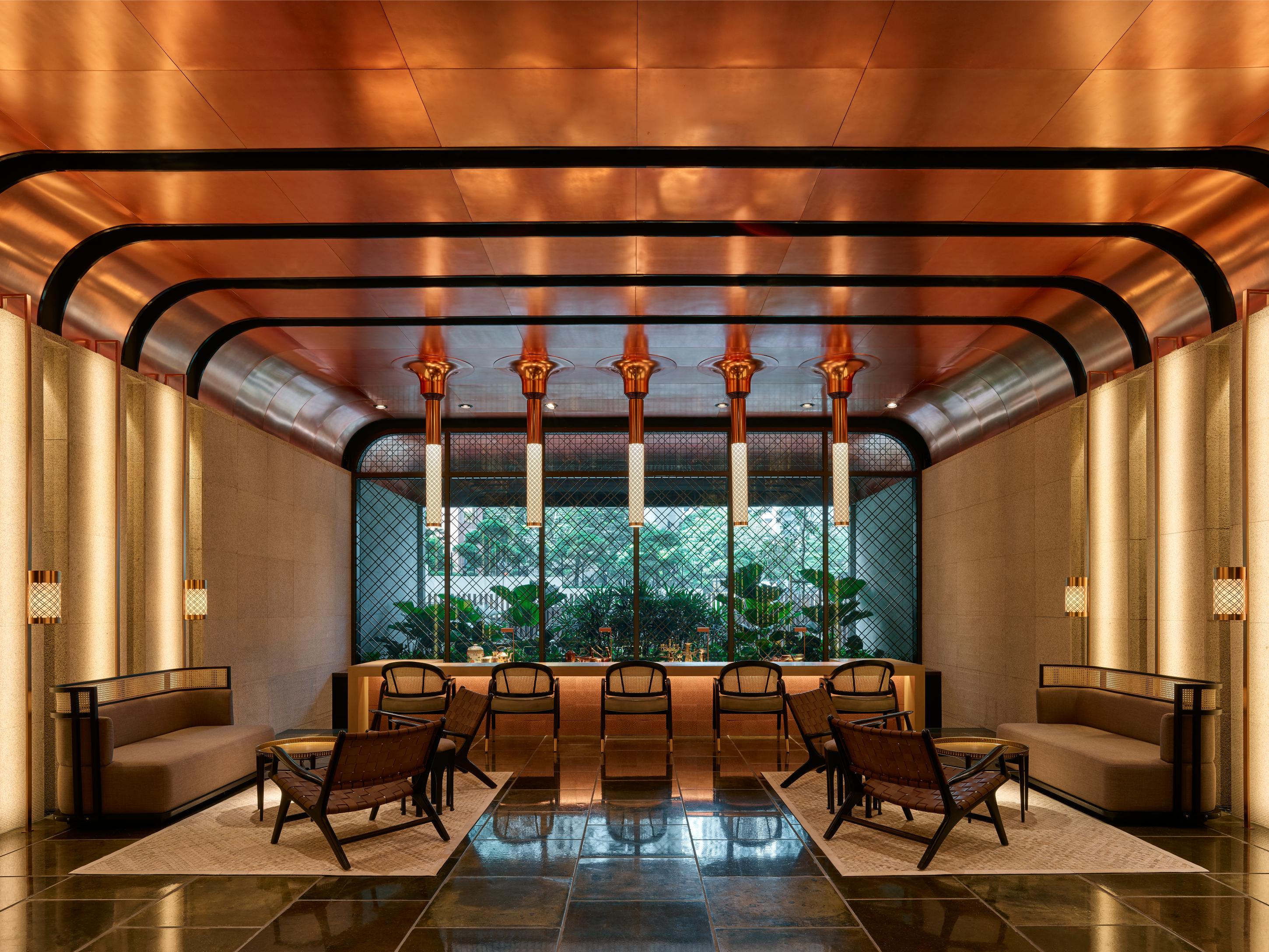 The Ruma Hotel And Residences Kuala Lumpur Kültér fotó The image shows a stylish interior space with a modern and elegant design. The walls have a sleek, warm-toned finish, and there are large windows that provide natural light. The ceiling features striking architectural lines, likely in a metallic mate